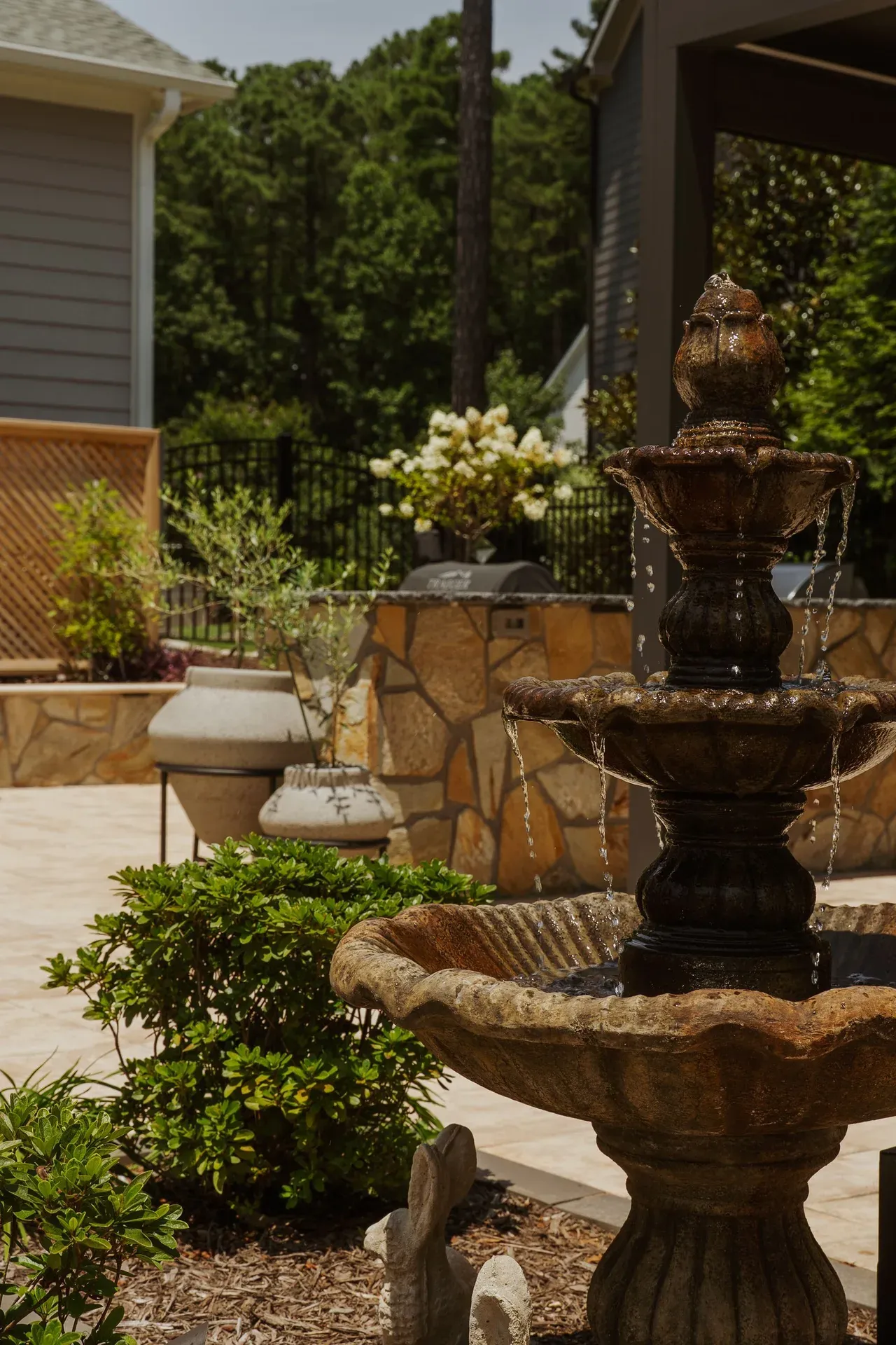Tiered stone fountain on a landscaped backyard patio